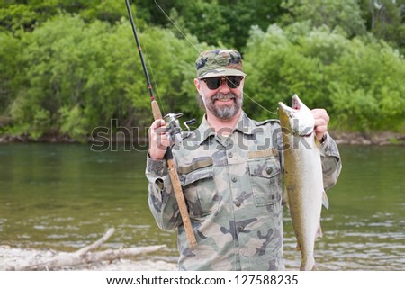Joyful fisherman holds caught pink salmon.
