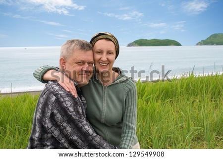 Happy middle aged couple outdoors by the sea.
