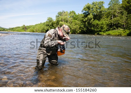 Fisherman drinking water from the river on a hot day.