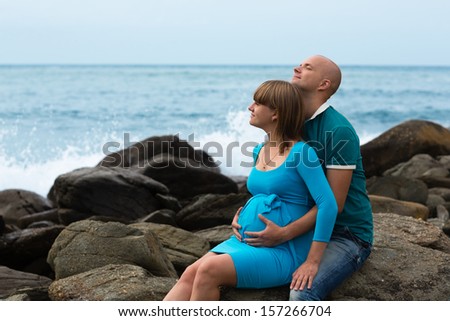 Happy pregnant woman and her husband on the sea coast.