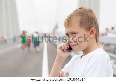 Boy talking on mobile phone. Golden Bridge during a holiday in Vladivostok.
