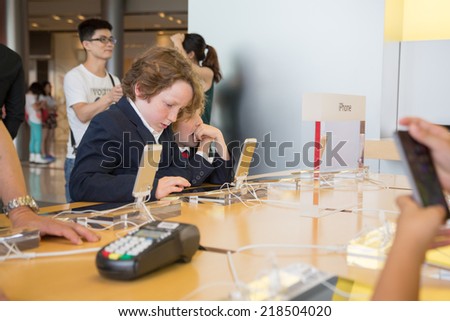 HONG KONG, CHINA - JUNE 15, 2014: Young visitors at Apple store in Hong Kong. Store is in a shopping center IFC Mall, it is very popular with locals and tourists visiting Hong Kong.