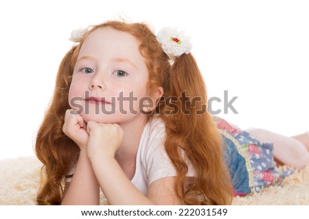 Little red haired girl lying on the carpet. The girl is six years old.