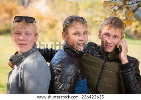 Group of guys talking in the autumn park, two of the boys twin brothers.