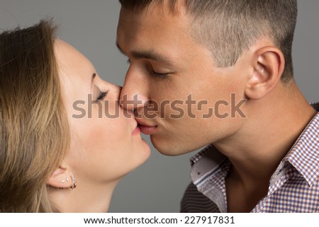 Happy young couple in love kissing on a background of gray wall