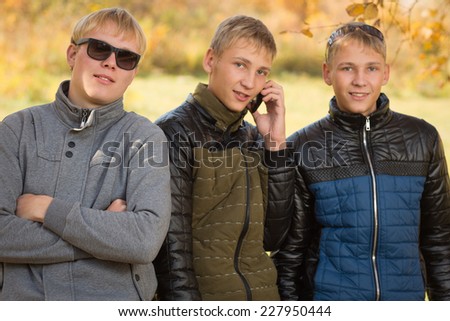 Portrait of a group of young men standing in autumn park, two of the boys twin brothers. Image with Instagram-like filter