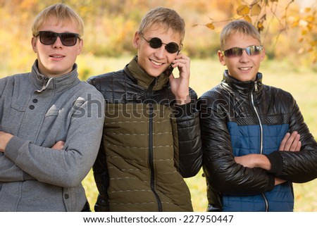 Three guys in autumn jacket and sunglasses, two of the boys twin brothers. Image with Instagram-like filter