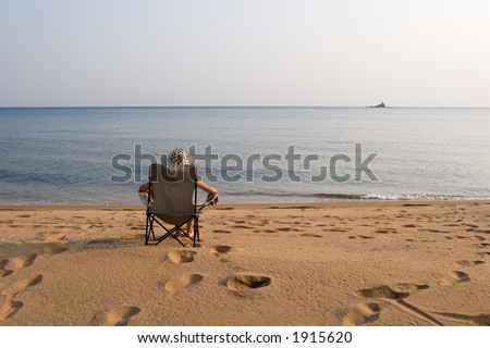 Lady sits on a chair at the sea in the autumn evening.
