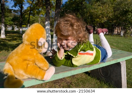 The little girl lays on a bench and \