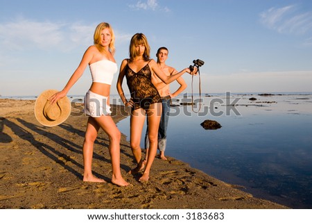 Young girls and the guy on a beach at the sea.In a hands the old binocular and hat.Evening.