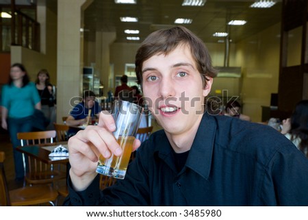 The young man drinks juice from a glass. Restaurant.