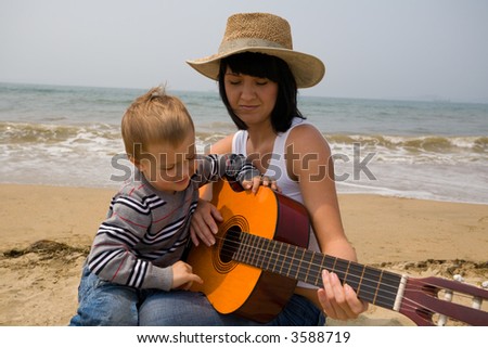 Mom learns(teaches) to play the son on a guitar. Above the sea a fog.
