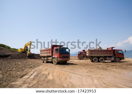 Construction of new seaport.Excavator loads a dump truck an earthen ground