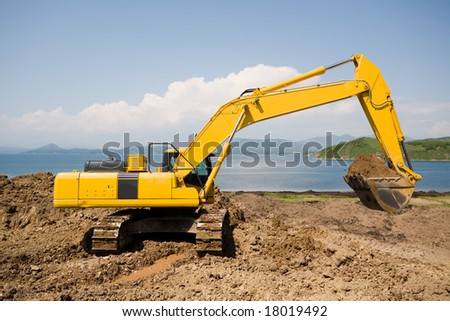 Excavator on the workplace on a background of the sea.