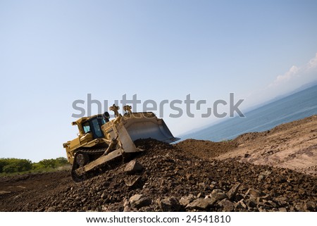 The bulldozer on a building site.On a background the sea.