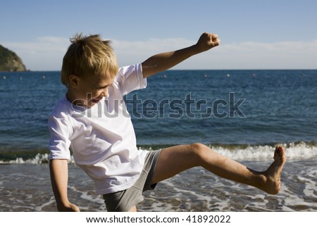 A young boy doing karate moves. Beach.