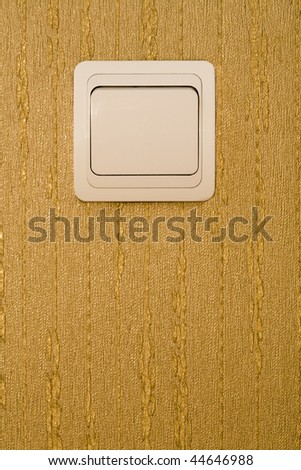 Light switch on a wall with wallpaper of gold color -  place for the text.