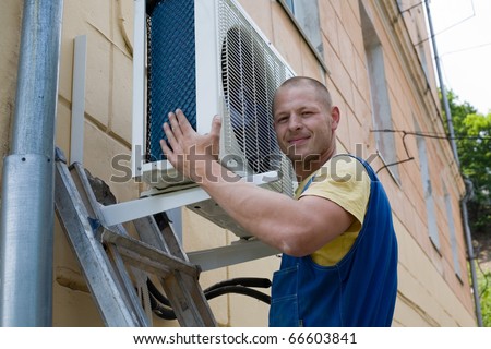 Young setup man installs the new air conditioner for office.