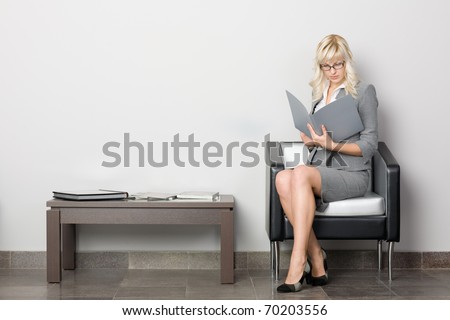 Attractive young business woman sitting in a chair. Waiting room.