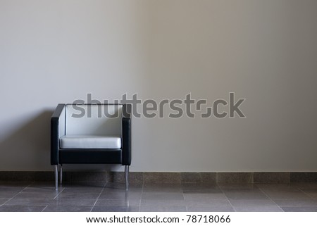 Modern lounge chair against a gray wall. Daylight.