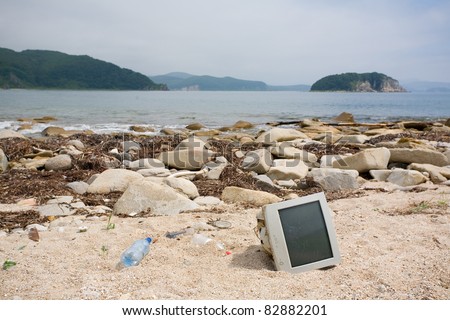 Ecology. Old computer monitor lying discarded on the shore of the sea.