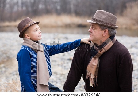 Grandfather and grandson looking at each other. Autumn. At the river.