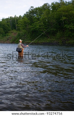 Fisherman standing in the river and catching salmon. Morning.