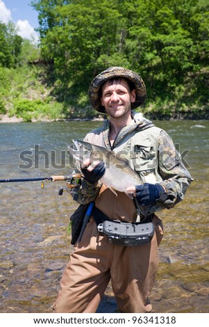 Happy fisherman keeps caught masu salmon (or cherry salmon). Russia. Primorskiy  kray.