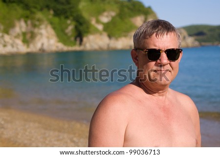 Handsome middle aged man sunbathes on the beach