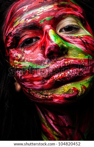 Close-up portrait of an artistic woman painted with red & green color. Part of face photo.