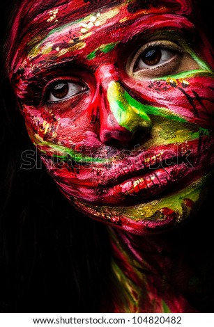 Close-up portrait of an artistic woman painted with red & green color. Part of face photo.