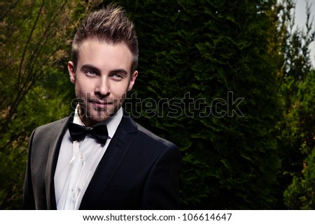 Portrait of young beautiful fashionable man against summer garden.