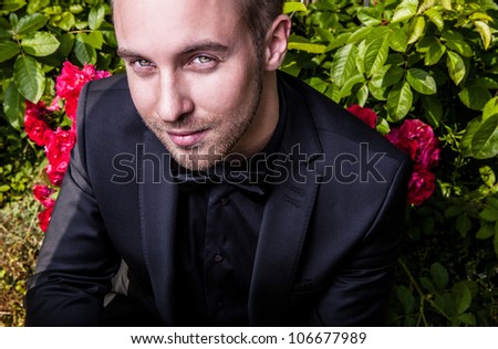 Portrait of young beautiful fashionable man against summer garden.
