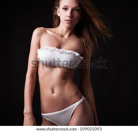 Pretty tanned woman in bikini on black background.
