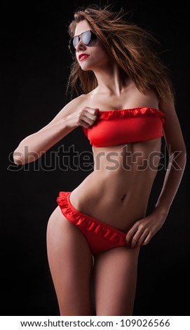 Pretty tanned woman in bikini on black background.