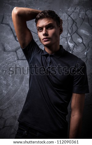 Elegant young handsome man on grunge background. Studio fashion portrait.