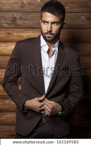 Portrait of young beautiful fashionable man against wooden wall.