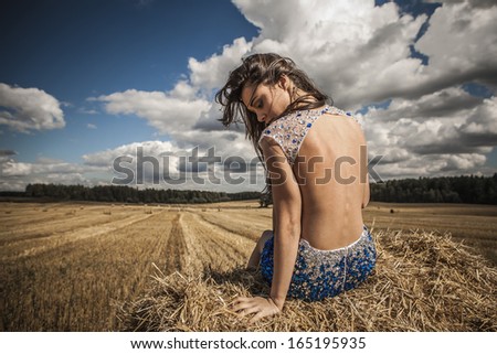 Young sensual & beauty woman in a fashionable white-blue dress pose on field.