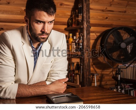 Portrait of young handsome man in white suit near home bar.