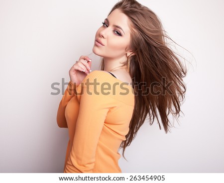 Young sensual & beauty model girl iin casual orange sweater pose in studio.
