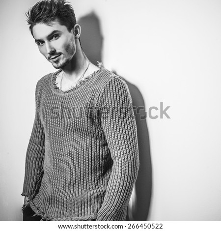 Black-white studio portrait of young handsome man in knitted sweater. Close-up photo.
