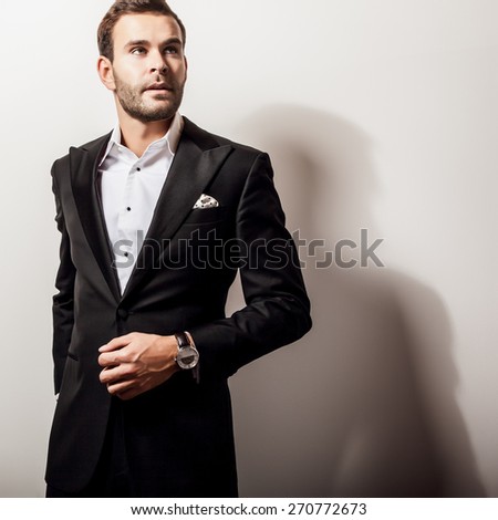 Elegant young handsome man in luxury black costume. Studio fashion portrait.
