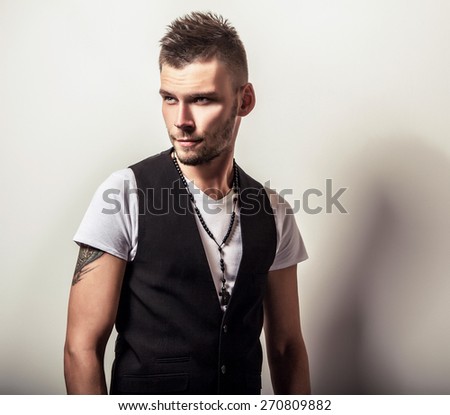 Studio portrait of young handsome man in casual white t-shirt & black vest. Black-white close-up photo.