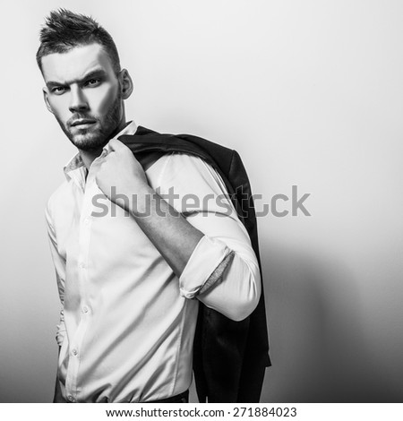Elegant young handsome serious man in white shirt with jacket. Black-white studio fashion portrait.