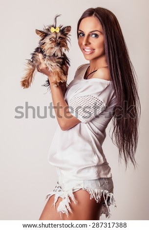 Young attractive friendly woman with Yorkshire Terrier dog. Studio photo.