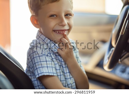 Outdoor portrait of happy blond little boy who explore salon of sport auto.