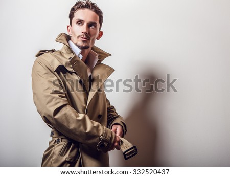 Elegant young handsome man in long stylish coat. Studio fashion portrait.