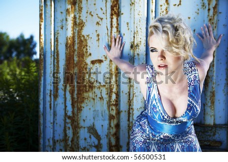 Elegant lady in an cocktail dress against old rusty container. Photo with copy-space.