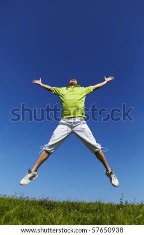 Jumping up guy in a green shirt against blue sky.