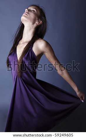 Sexy brunette posing in silk violet dress.